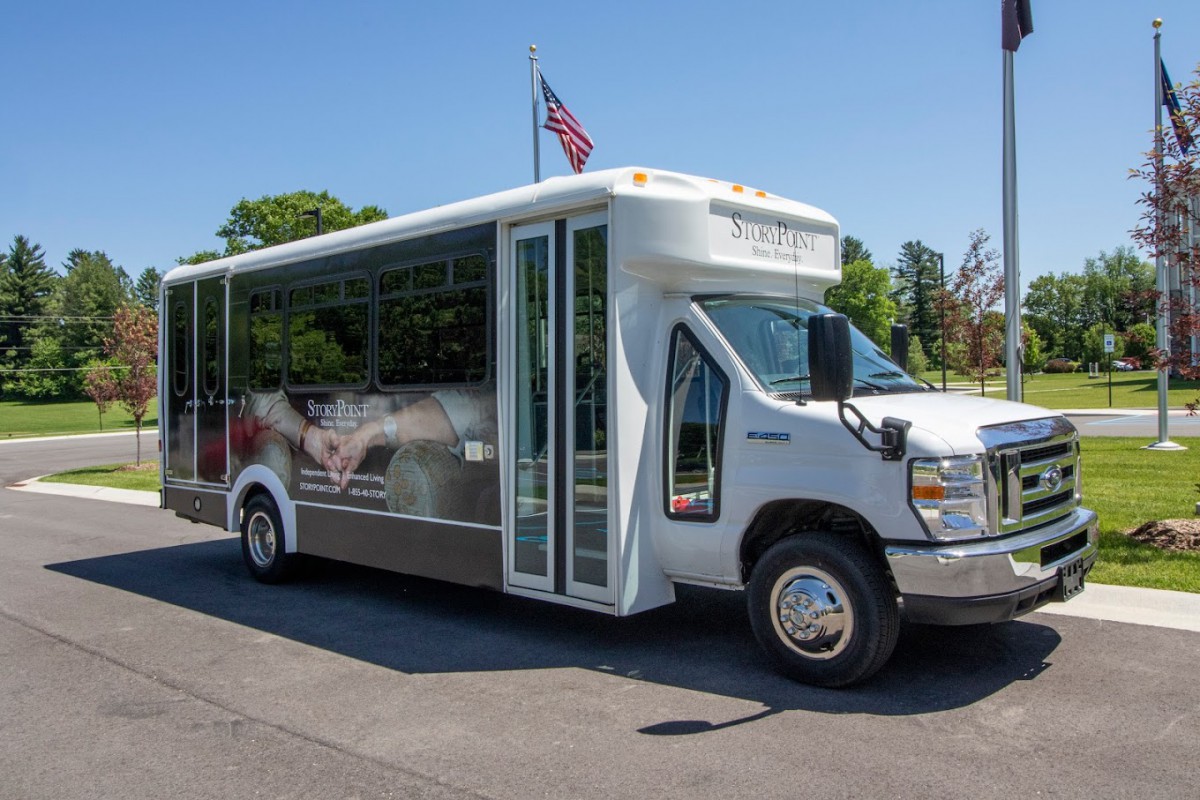 A white shuttle bus parked on the road in daylight.