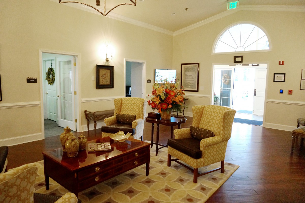 A cozy living room with elegant armchairs, a wooden coffee table, and decorative elements like flowers and wall art.
