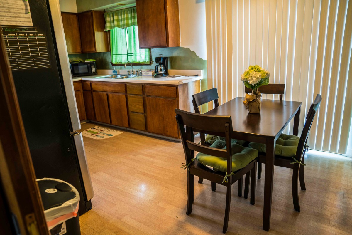A cozy kitchen and dining area featuring wooden cabinets and a dining table with chairs, adorned with a flower arrangement.