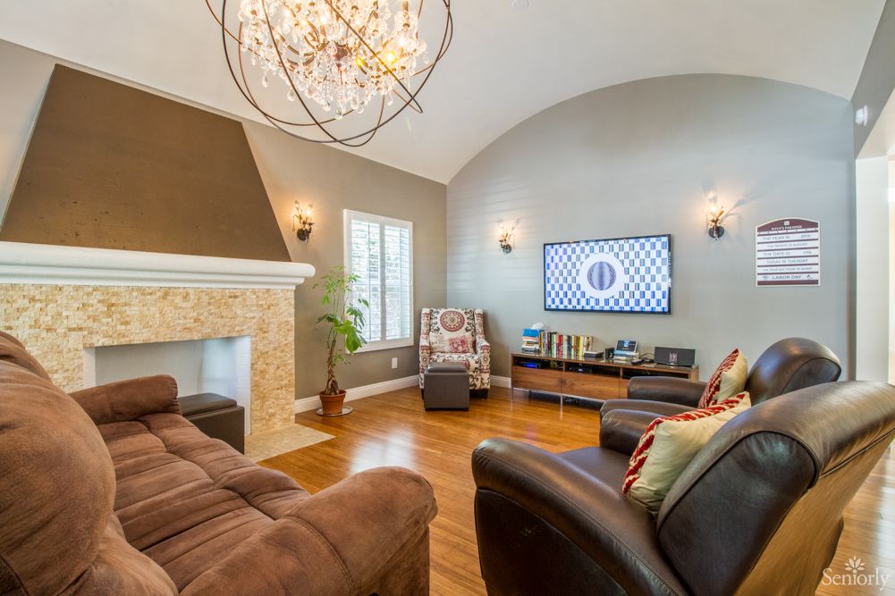 A stylish living room with a modern chandelier, cozy sofas, and a fireplace.