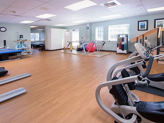 A well-lit gym interior featuring various exercise equipment and a wooden floor.