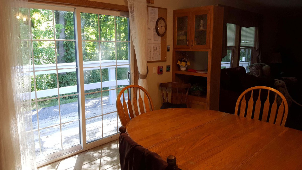 A cozy dining area with a wooden table and chairs, adjacent to a sliding glass door leading to a deck.