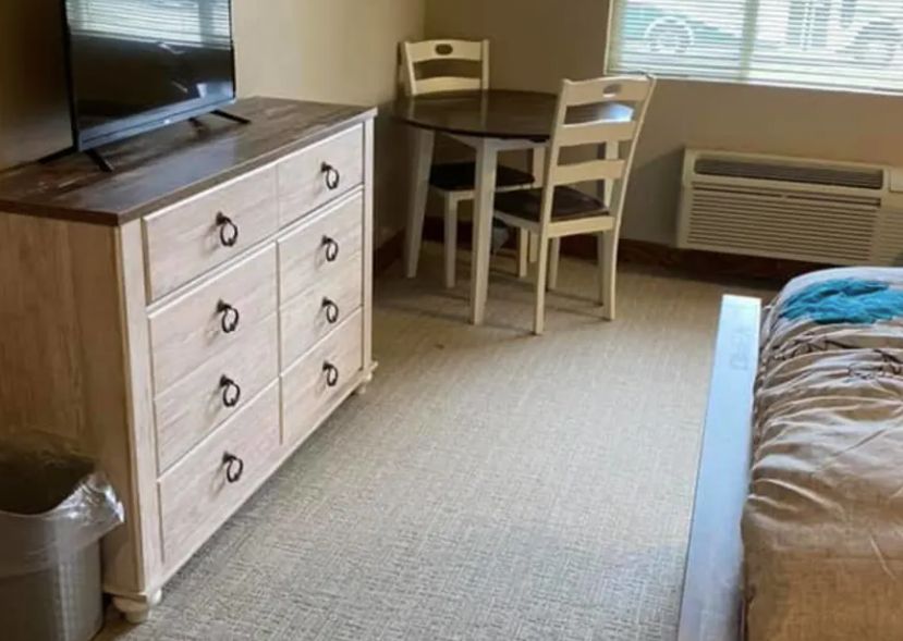 A cozy room with a dresser, table, and chairs.