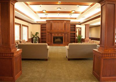 A cozy living room featuring wooden paneling, a central fireplace, and comfortable sofas.
