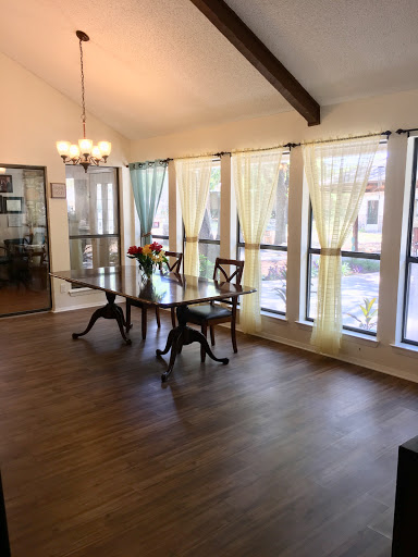 A bright and elegant dining room featuring a wooden table and large windows adorned with sheer curtains.