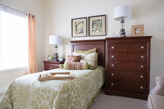 A cozy bedroom with elegant furniture and decor, including a bed, dresser, and lamps.