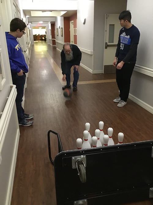 People enjoying an impromptu game of bowling in a hallway.