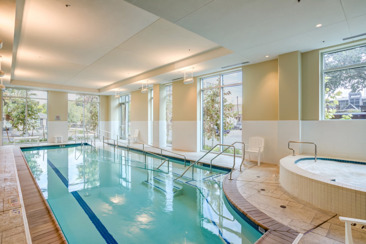 A modern indoor pool area with a jacuzzi and large windows providing natural light.