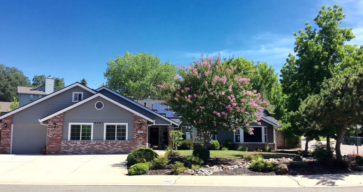 A suburban house with solar panels and well-maintained landscaping.
