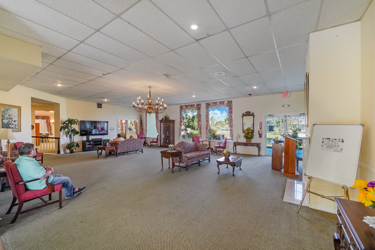 A spacious living room with elegant furnishings, a chandelier, and large windows allowing natural light to fill the space.