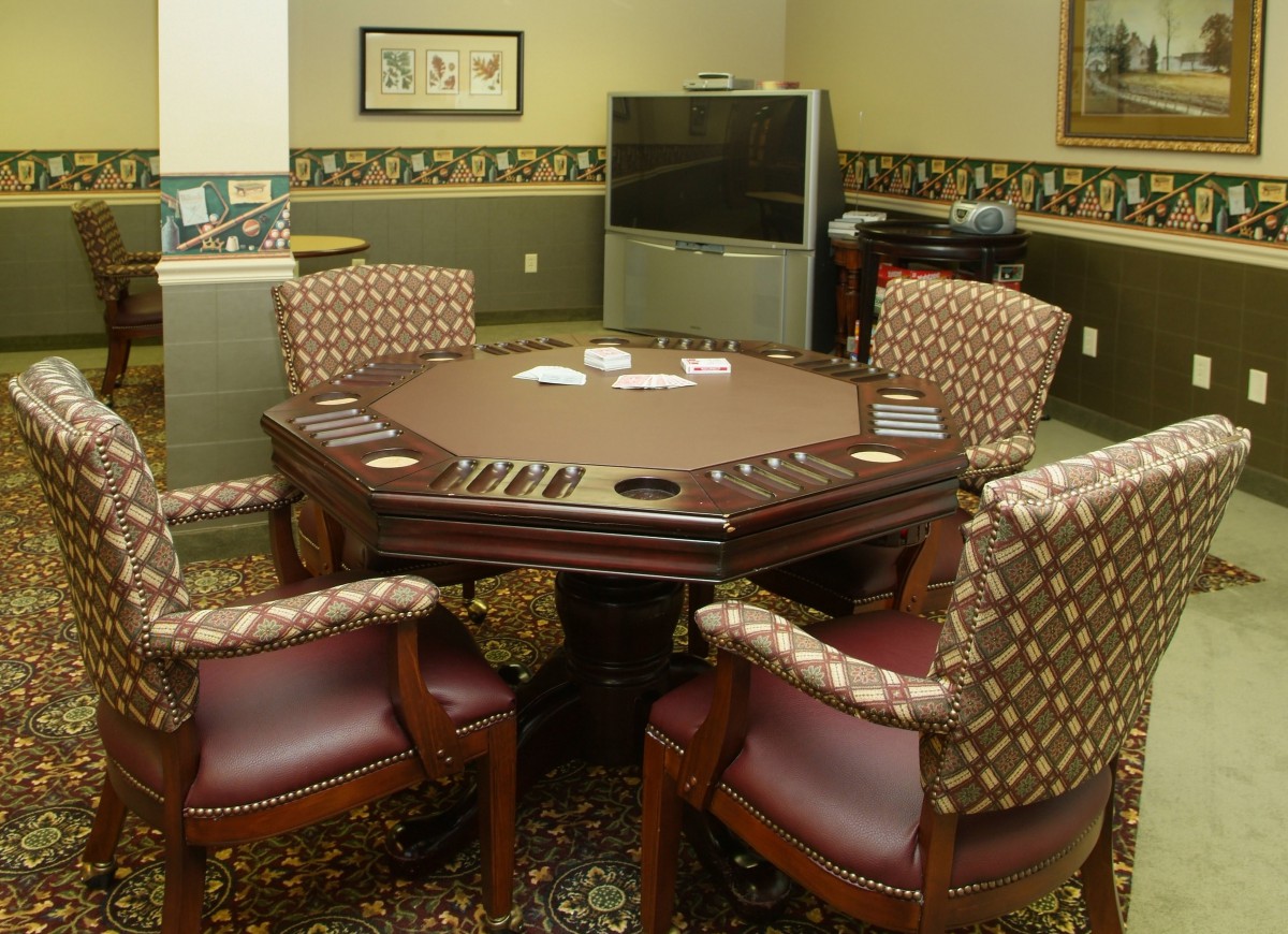 A cozy game room featuring a poker table surrounded by comfortable leather chairs, ready for a card game.