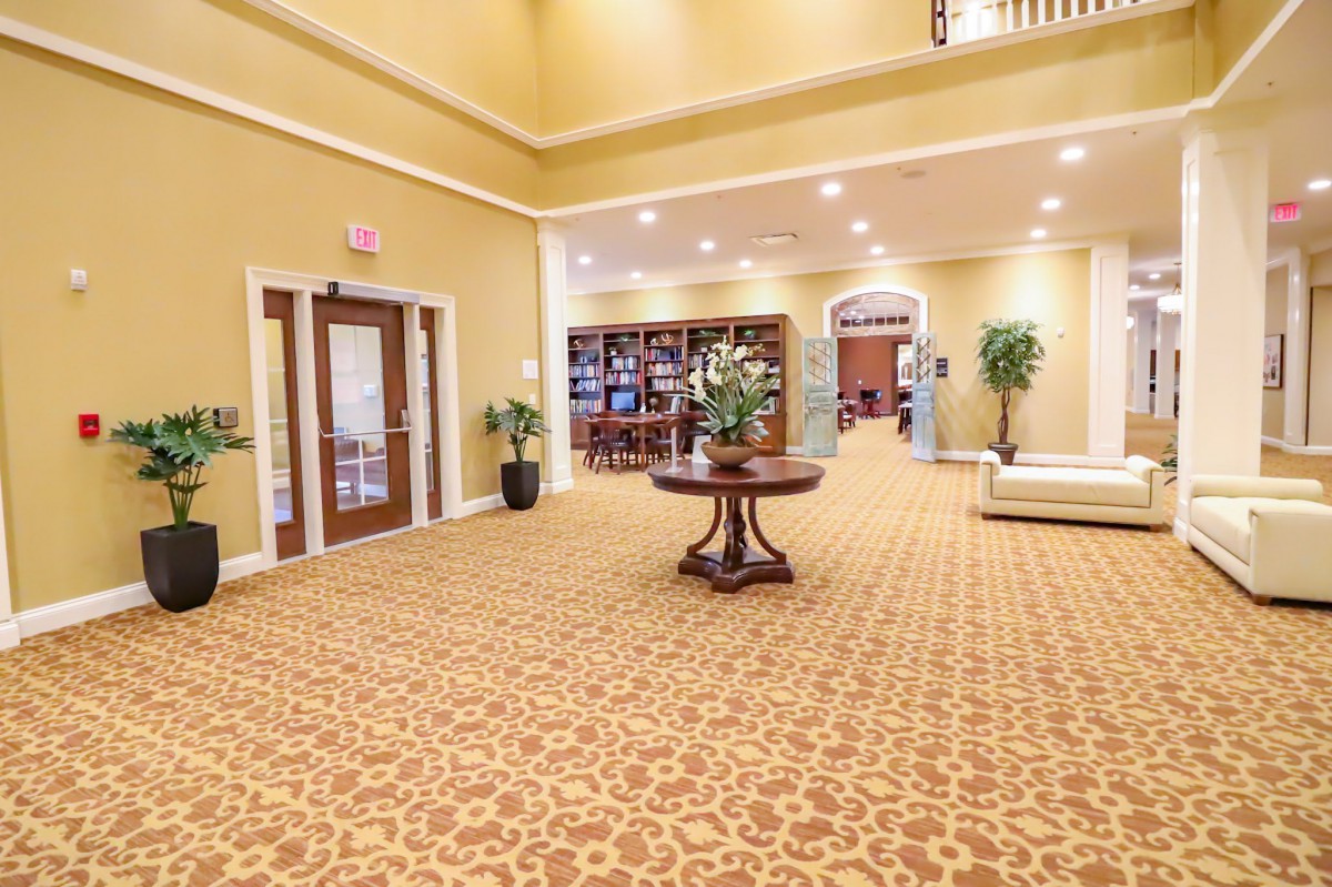 A spacious and elegantly designed lobby with a central wooden table, surrounded by comfortable seating and decorative elements.