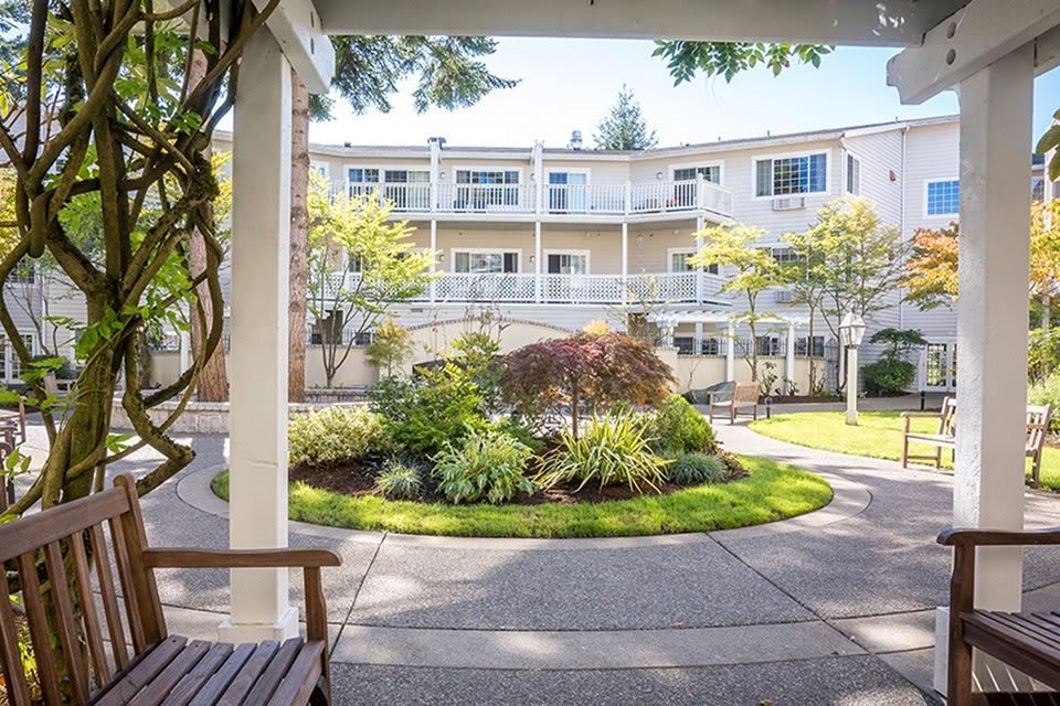 A well-maintained courtyard with a central garden and pathways, surrounded by a multi-story building on a sunny day.