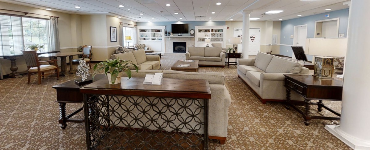A spacious and elegantly decorated living room with comfortable sofas, a central coffee table, a fireplace, and a television.