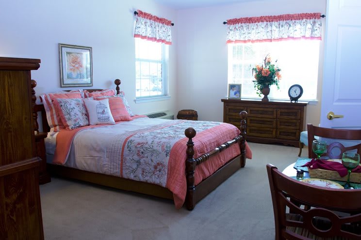 A cozy bedroom with a wooden bed frame and floral bedding, complemented by a large dresser and decorative accents.
