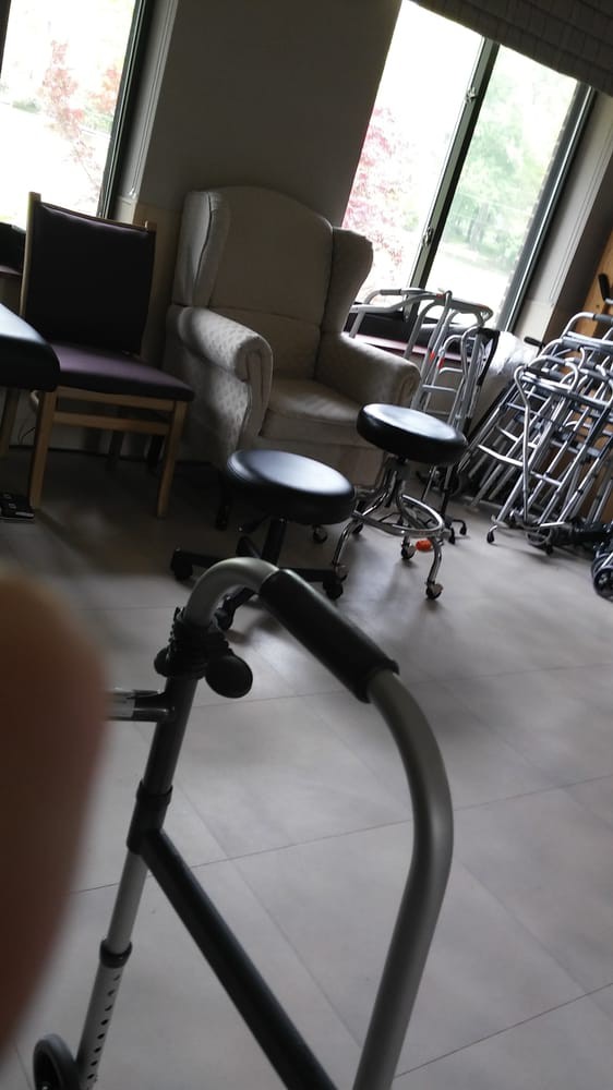 A collection of mobility aids, including wheelchairs and walkers, in a room.