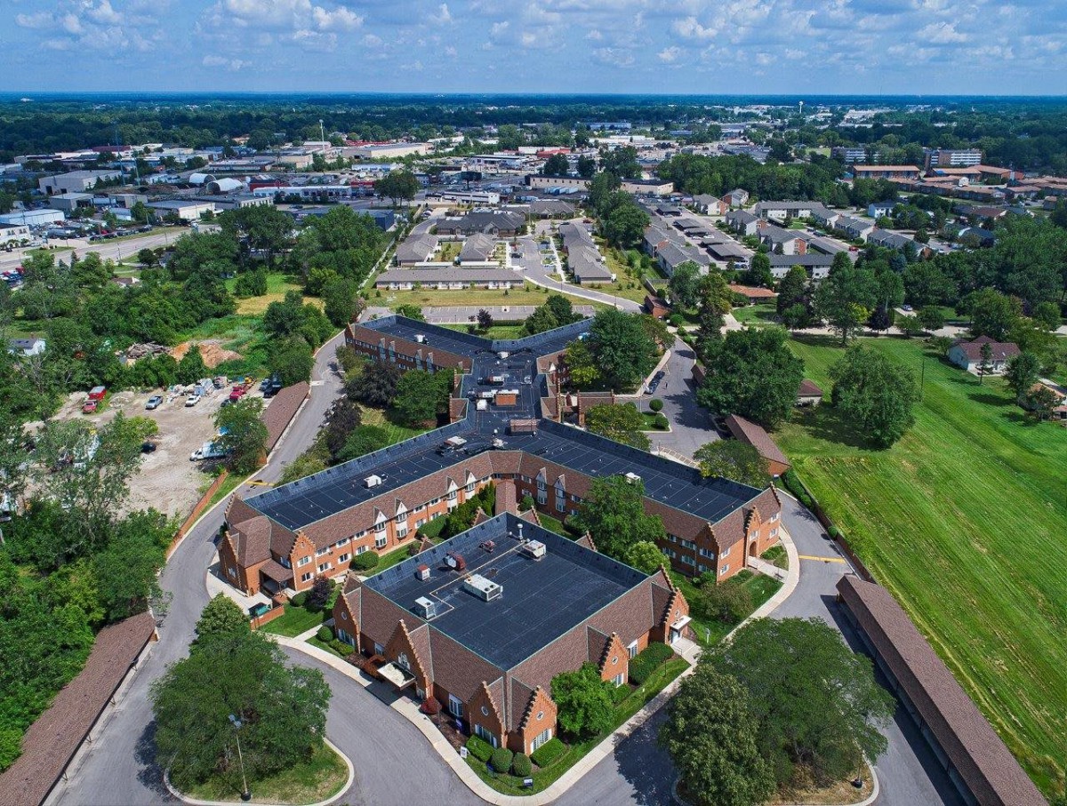 Aerial view of a residential and commercial area with roads and green spaces.