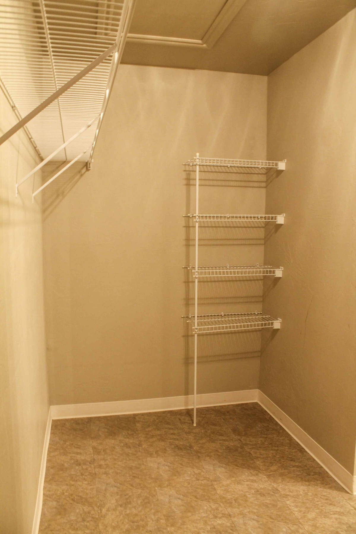 An empty walk-in closet with wire shelving and beige walls.
