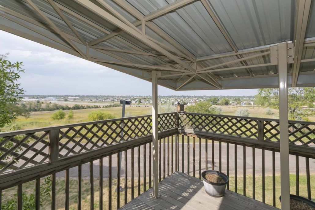 A covered porch with a view of a rural landscape.