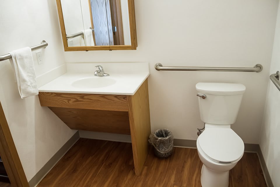 A clean and simple bathroom with a sink, toilet, and mirror.