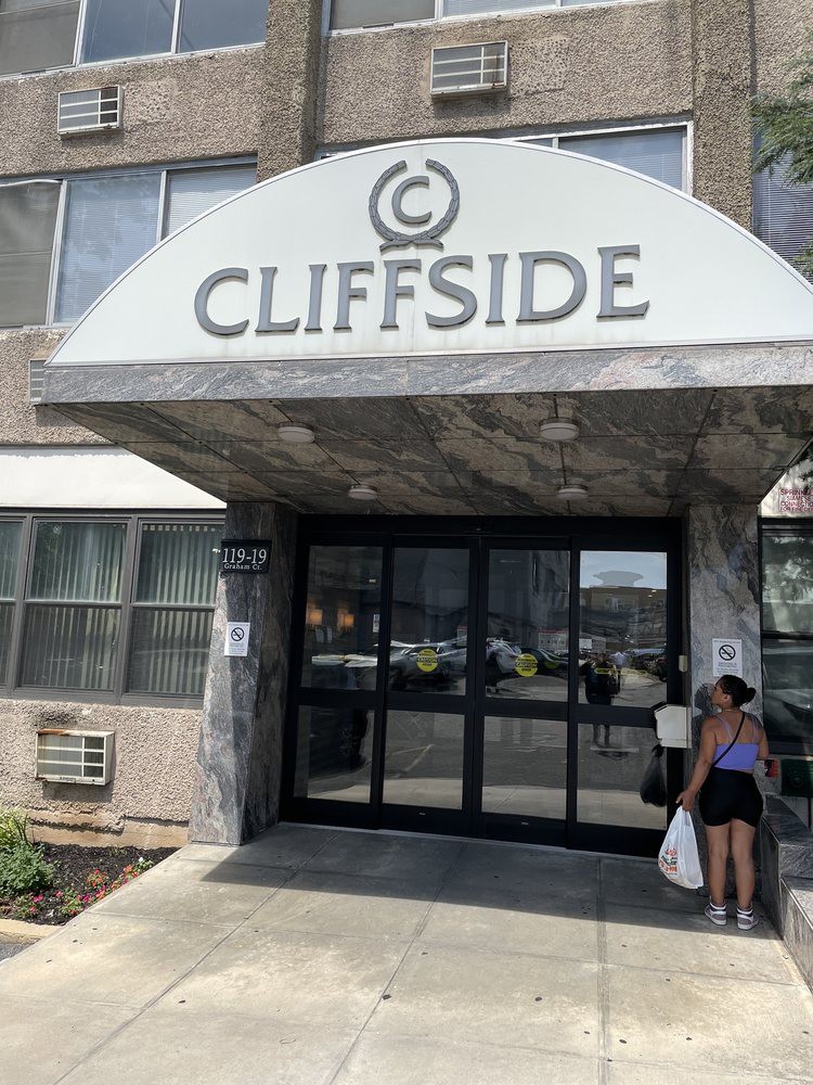 A person standing near the entrance of the Cliffside apartment building.