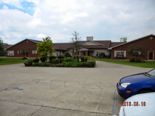 A view of a spacious brick building surrounded by well-maintained landscaping and a parking area.