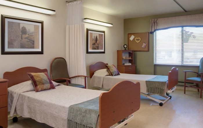 A shared hospital room with two beds and simple decor.