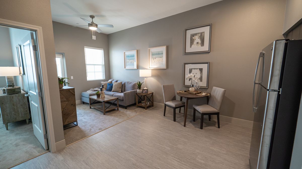 A modern living room with neutral tones featuring a sofa, chairs, and decorative artwork.