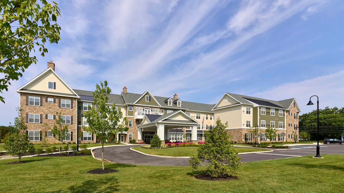 A large residential building with a well-maintained lawn under a clear blue sky.