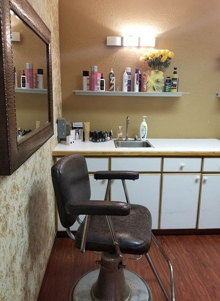 A small salon interior featuring a barber chair, mirror, and shelves with hair products.