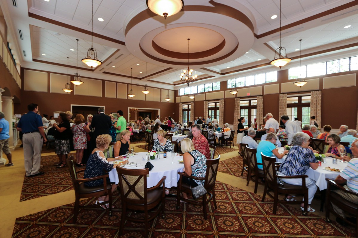 A large group of people dining and socializing at an indoor banquet event.