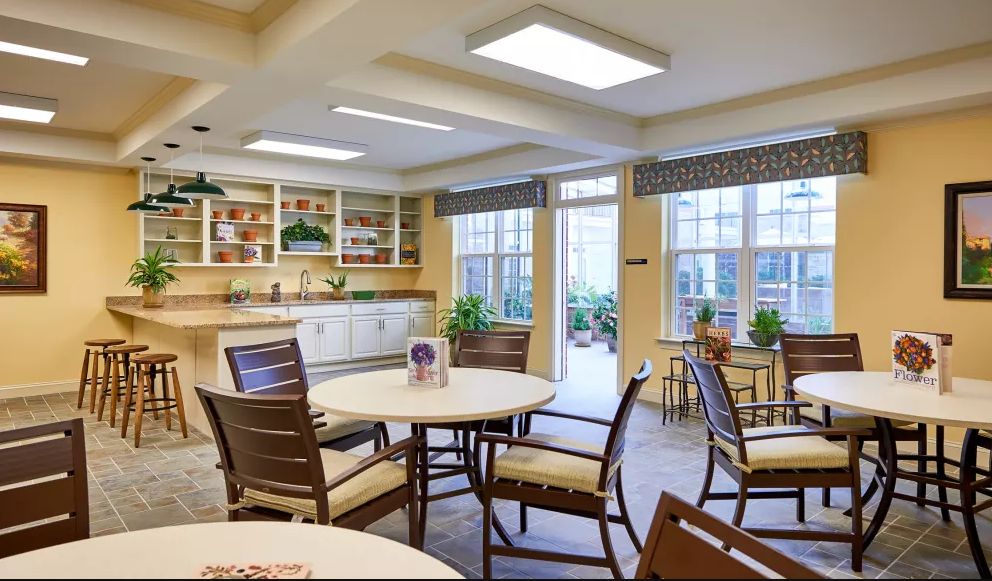 A bright dining area with tables, chairs, and large windows letting in natural light.