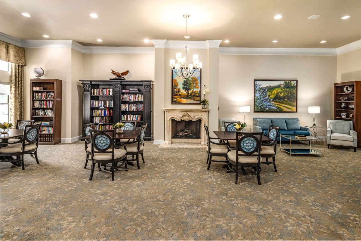 A cozy living room with a fireplace, bookshelves, and arranged seating.