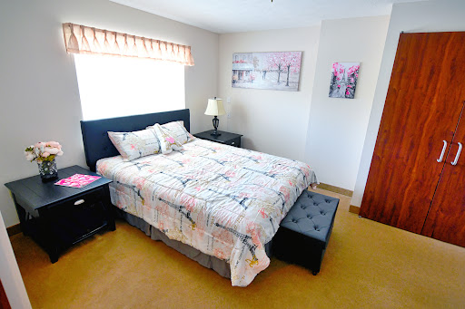 A cozy and well-decorated bedroom featuring a neatly made bed, elegant nightstands, and decorative artwork.
