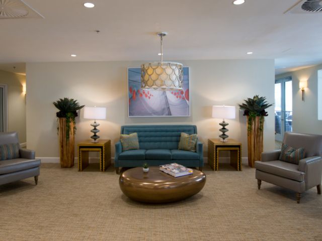A well-furnished lobby with a sofa, round table, artwork, and decorative lamps.