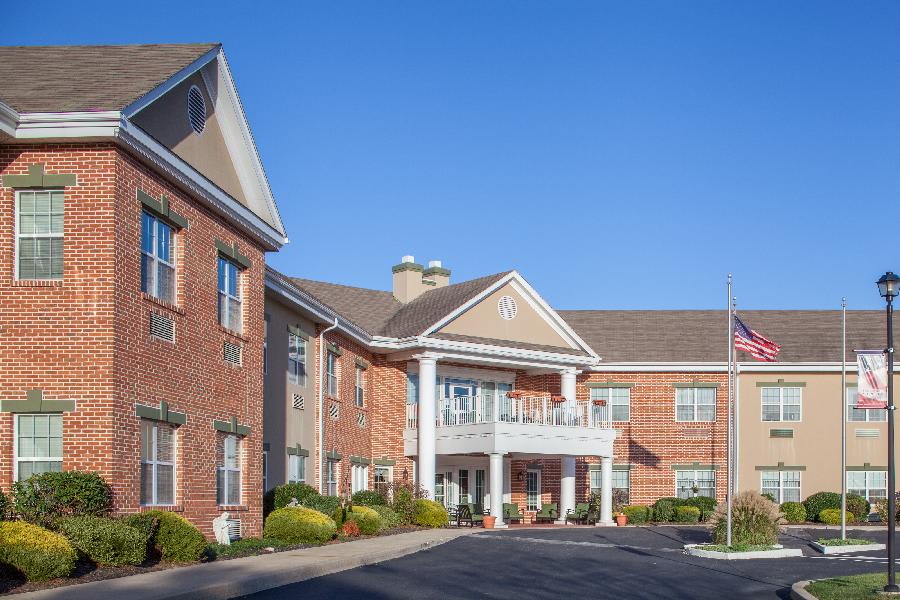 A two-story brick building with a grand entrance on a clear day.