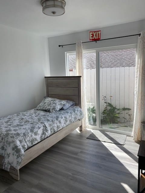 A minimalist bedroom with a single bed and sliding glass doors leading to an outdoor area.