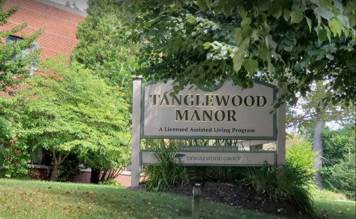 Sign for Tanglewood Manor surrounded by lush greenery.