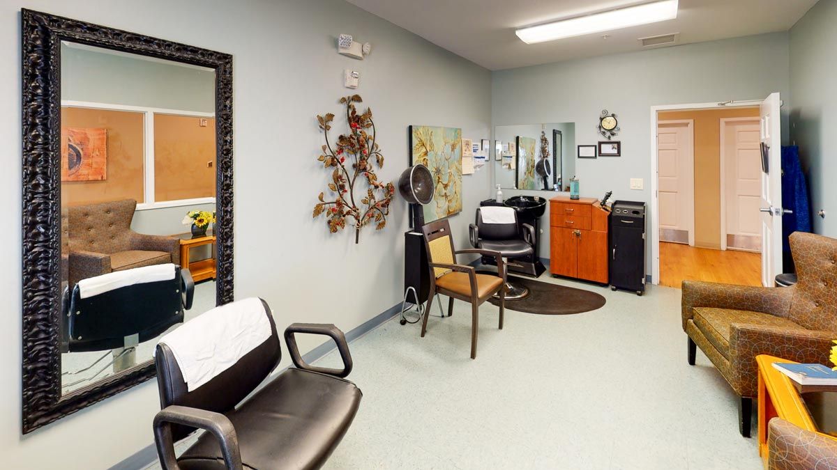 A cozy hair salon interior featuring chairs, a mirror, and styling equipment.