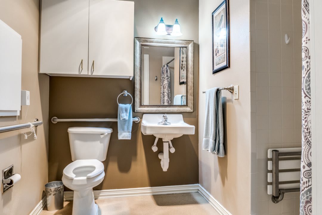 A neatly organized bathroom with a toilet, sink, mirror, and cabinet.