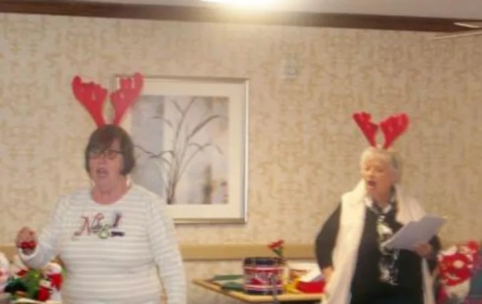 Two people wearing reindeer antlers at a festive indoor gathering.