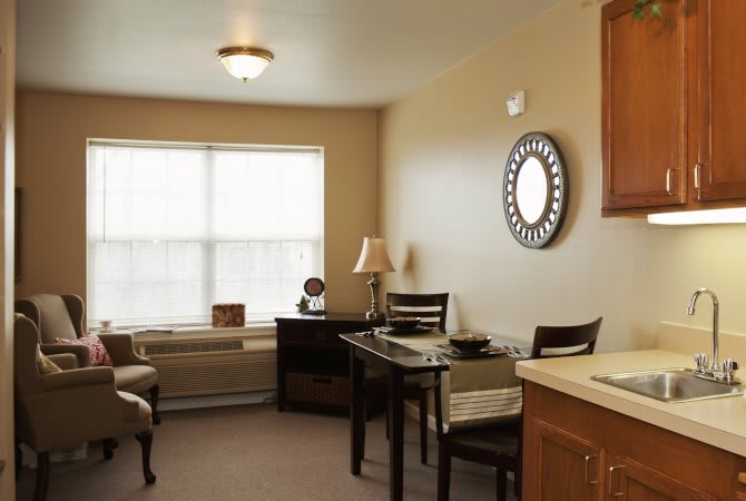 A cozy living area with a table and chairs, alongside a window and decorative mirror.