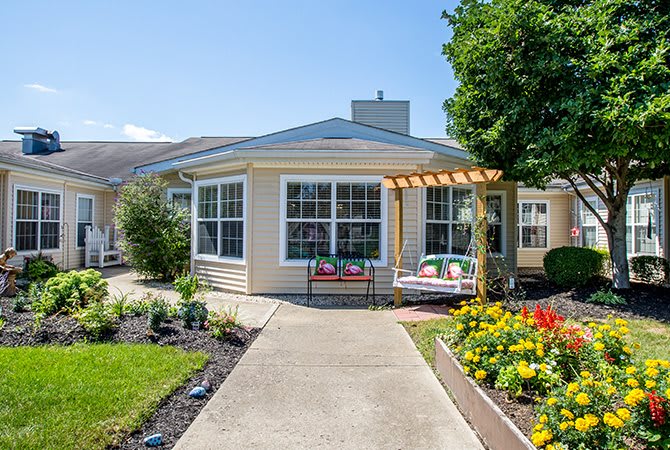 A charming house with a well-maintained garden and outdoor seating area on a sunny day.