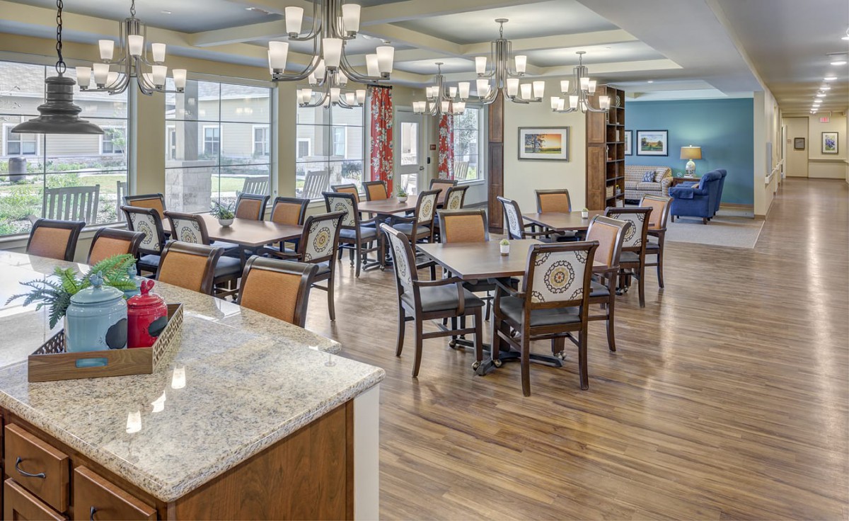 A spacious dining area with multiple tables, chairs, and elegant chandeliers.