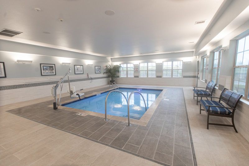 A modern indoor swimming pool with surrounding seating and ample lighting.