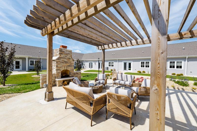 A beautifully furnished patio featuring a wooden pergola and outdoor fireplace.