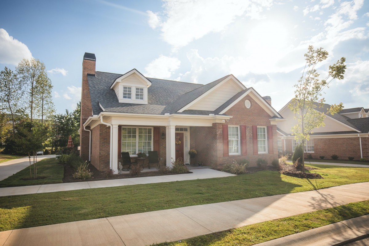 A picturesque suburban brick house with a well-maintained lawn.