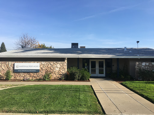 A well-maintained residential building with a grassy front yard and clear blue sky.