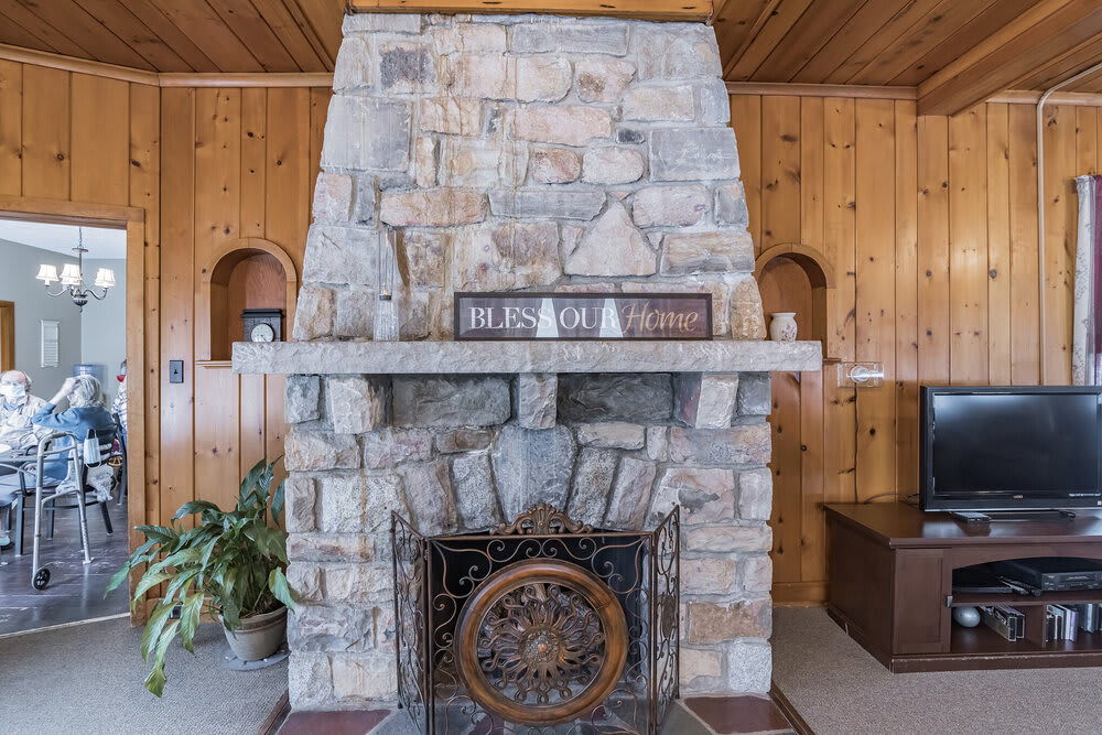 A rustic stone fireplace in a wood-paneled room with decorative accents.
