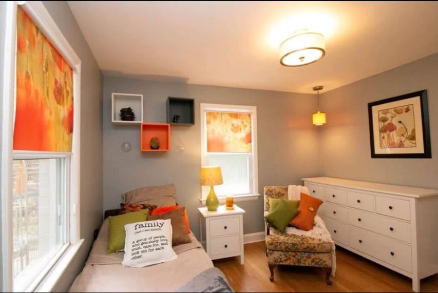 A cozy bedroom featuring modern decor with a bed, armchair, and bright accents.